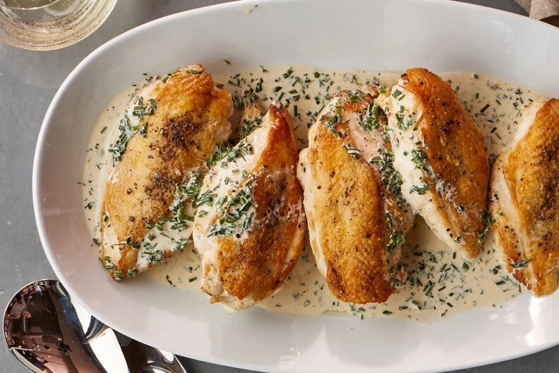 A plate of roast chicken served on top of a cream sauce.