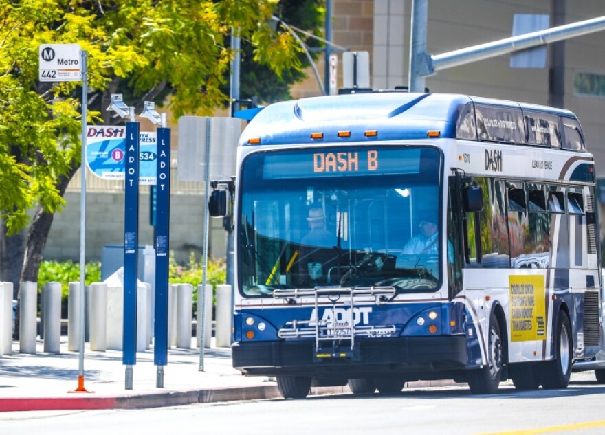 A bus traveling on a city stop makes a stop at signs labeled: LADOT and DASH B