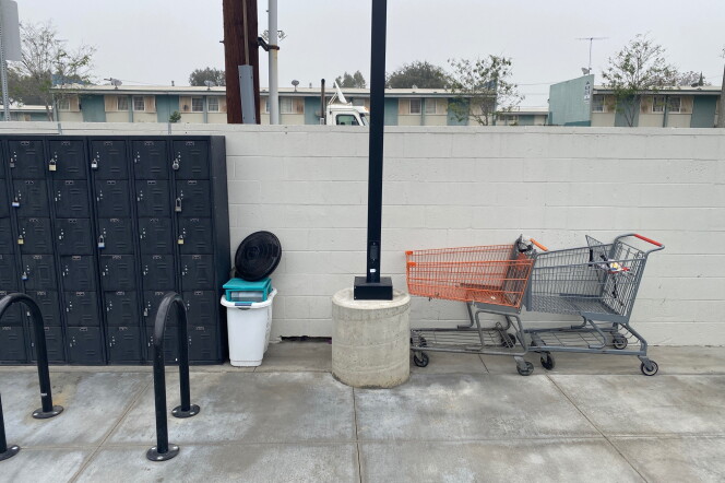 a wall of gray storage lockers, a bike rack, a lamp post and two shopping carts 