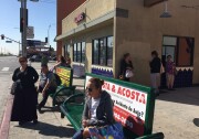 Some passengers seek shade, others wait in the sun on a weekday morning at a bus stop with no bus shelter on San Fernando Road in Pacoima.