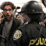SAN FRANCISCO, CA - AUGUST 15:  A protestor pretends to talk on a cell phone as he taunts a Bay Area Rapid Transit (BART) police officer at the Civic Center station on August 15, 2011 in San Francisco, California.  The hacker group "Anonymous" staged a demonstration at a BART station this evening after BART officials turned off cell phne service in its stations last week during a disruptive protest following a fatal shooting of a man by BART police.  (Photo by Justin Sullivan/Getty Images)