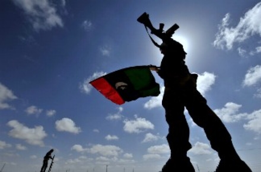 A Libyan anti-Kadhafi fighter waves the flag of the rebellion on a desert road some 30 kilometers from the eastern town of Brega on March 31, 2011.