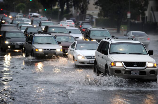 People drive their cars through deep water in Los Angeles, California, on December 22, 2010. Downtown Los Angeles received one-third of its annual average rainfall in less than a week. As of midmorning yesterday, the rain gauge at the University of Southern California campus recorded 5.77 inches.  