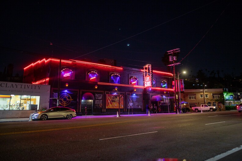The exterior of a nightclub with black walls and bright red neon light trim around its edges. There's a red sign that's lit up and reads "Los Globos" in white text.