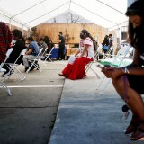 LOS ANGELES, CALIFORNIA - APRIL 10: Volunteer Miriam Lopez Ambrosio (C), a folkloric dancer from Oaxaca, waits to assist people with their vaccination appointments at a clinic targeting Central American Indigenous residents at CIELO, an Indigenous rights organization, on April 10, 2021 in Los Angeles, California. CIELO launched an outreach campaign for vaccinations to address language barriers, accessibility, mistrust of government and misinformation among Mexican and Guatemalan Indigenous residents. They have suffered disproportionately during the pandemic with many losing work in the hospitality industry. St. John's Well Child and Family Center is administering COVID-19 vaccines across South L.A. in a broad effort to bring vaccines to minority communities. (Photo by Mario Tama/Getty Images)