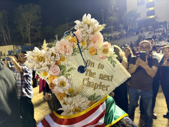 The back of a mortarboard reads "on to the next chapter," while decorate with flowers and cut-out book pages.