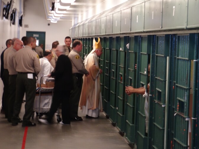                                Archbishop José H. Gomez offers communion to inmates at Los Angeles County Men's Central Jail who were not permitted to attend mass with other inmates. Alongside Gomez is Los Angeles County Sheriff Jim McConnell.