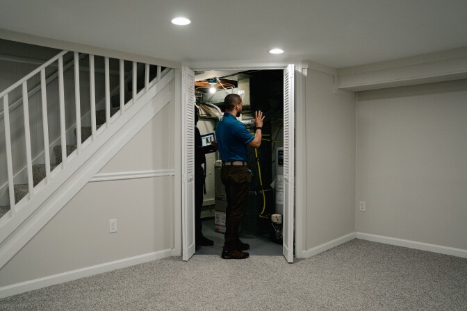A person with dark-tone skin looks into a close in what appears to be a basement.