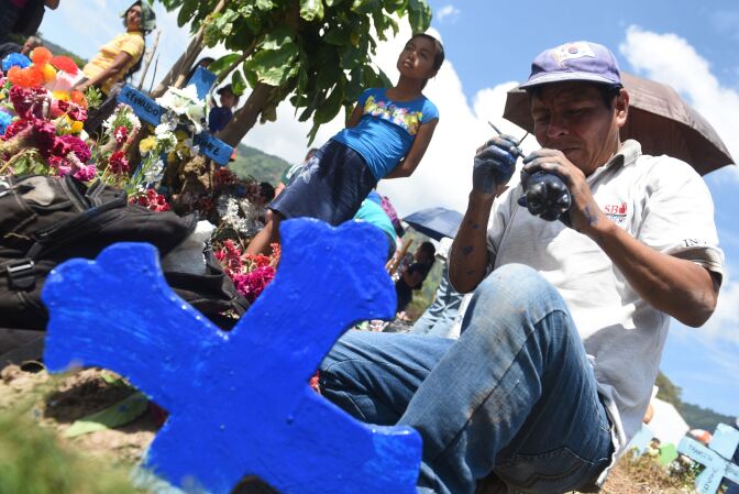 A man makes improvements to the grave of a loved one during the commemoration of the day of the dead at a cemetery in Panchimalco, El Salvador on November 2, 2016.