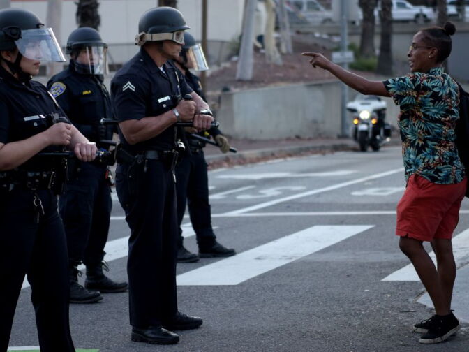 A woman gestures to a row of police officers as protesters gather in downtown Los Angeles on May 27, 2020 to demonstrate after George Floyd, an unarmed black man, died while being arrested by a police officer in Minneapolis who pinned him to the ground with his knee. - Outrage has grown across the country at Floyd's death on May 25, fuelled in part by bystander cellphone video which shows him, handcuffed and in the custody of four white police officers, on the ground while one presses his knee into the victim's neck. (Photo by Agustin PAULLIER / AFP) (Photo by AGUSTIN PAULLIER/AFP via Getty Images)