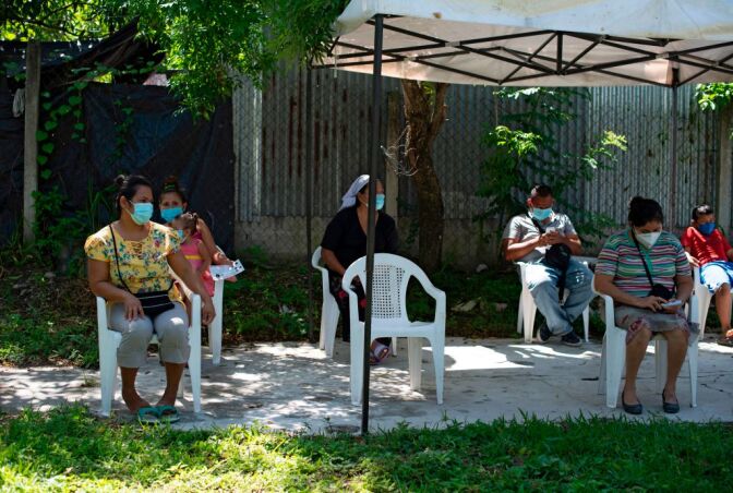 Residents maintain social distance while waiting to see a doctor in a clinic of the organization Doctors Without Borders (MSF) installed at the December 1 community in Soyapango, El Salvador, on July 30, 2020, amid the new coronavirus pandemic. - MSF became the only hope of medical assistance for people who live in areas under the influence of violent gangs in El Salvador, where the state healthcare system does not reach. (Photo by Yuri CORTEZ / AFP) (Photo by YURI CORTEZ/AFP via Getty Images)