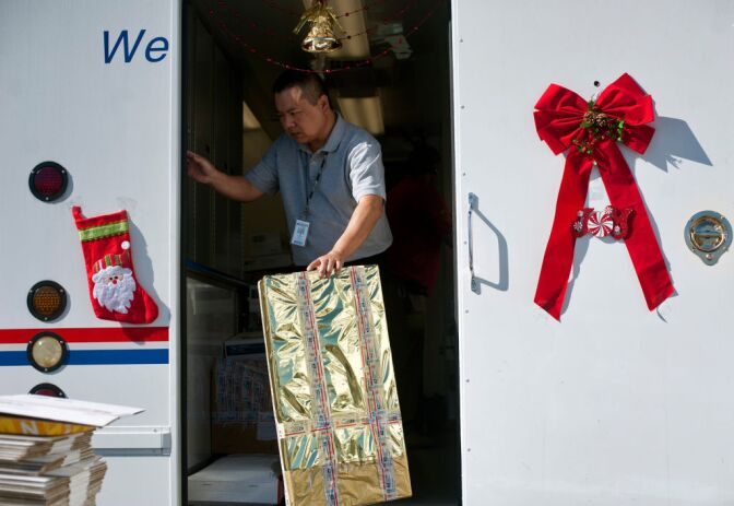 USPS Retail Specialist Phillip Chan gathers gifts that are ready to be mailed as part of Operation Santa on Thursday, Dec. 20. Letters addressed to Santa stay in the area where they were mailed. Volunteers can come in at any time to "adopt" letters, and return to the post office with a gift.