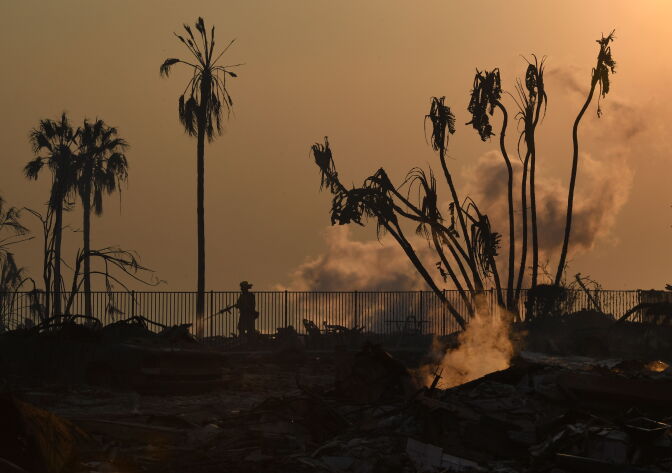 A firefighter hoses down flareups at the two story Hawaiian Village Apartment complex that burnt to the ground during the Thomas wildfire in Ventura, California on December 5, 2017.
Firefighters battled a wind-whipped brush fire in southern California that has left at least one person dead, destroyed more than 150 homes and businesses and forced tens of thousands to flee. / AFP PHOTO / MARK RALSTON        (Photo credit should read MARK RALSTON/AFP/Getty Images)