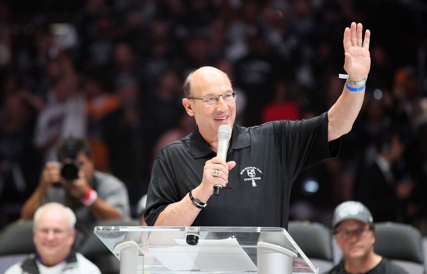 File: Los Angeles Kings play-by-play television announcer Bob Miller addresses the fans as General Manager Dean Lombardi (bottom right) and Assistant to the General Manager Jack Ferreira (bottom left) look on during the rally in Staples Center after the Los Angeles Kings Stanley Cup Victory Parade on June 14, 2012.