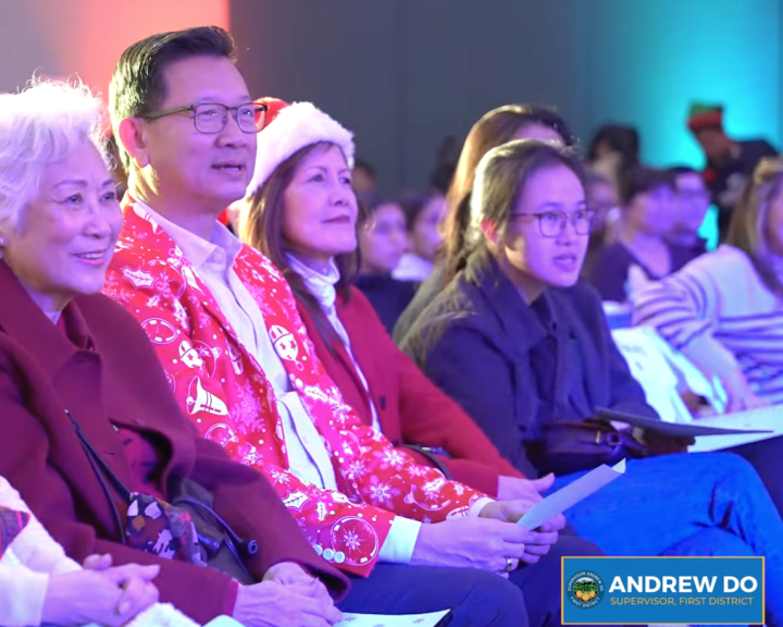 From left to right, an Asian woman with white hair sits next to an Asian man wearing glasses. Next to him is an Asian woman in a Santa hat and a younger Asian woman with glasses and her hair tied back.