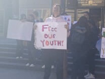 Floyd Lee Hardge stands outside the Board of Supervisors meeting holding a sign that reads "Free Our Youth!" 