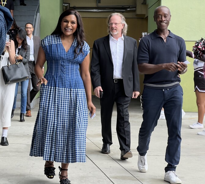 Mindy Kaling and Don Cheadle walk towards the camera while touring a school.