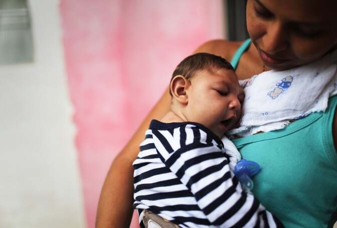 RECIFE, BRAZIL - MAY 30:  Mother Daniele Santos holds her baby Juan Pedro, who has microcephaly, on May 30, 2016 in Recife, Brazil. Microcephaly is a birth defect linked to the Zika virus where infants are born with abnormally small heads. The city of Recife and surrounding Pernambuco state remain the epicenter of the Zika virus outbreak, which has now spread to many countries in the Americas. A group of health experts recently called for the Rio 2016 Olympic Games to be postponed or cancelled due to the Zika threat but the WHO (World Health Organization) rejected the proposal. The Olympic torch passes through Recife May 31.  (Photo by Mario Tama/Getty Images)