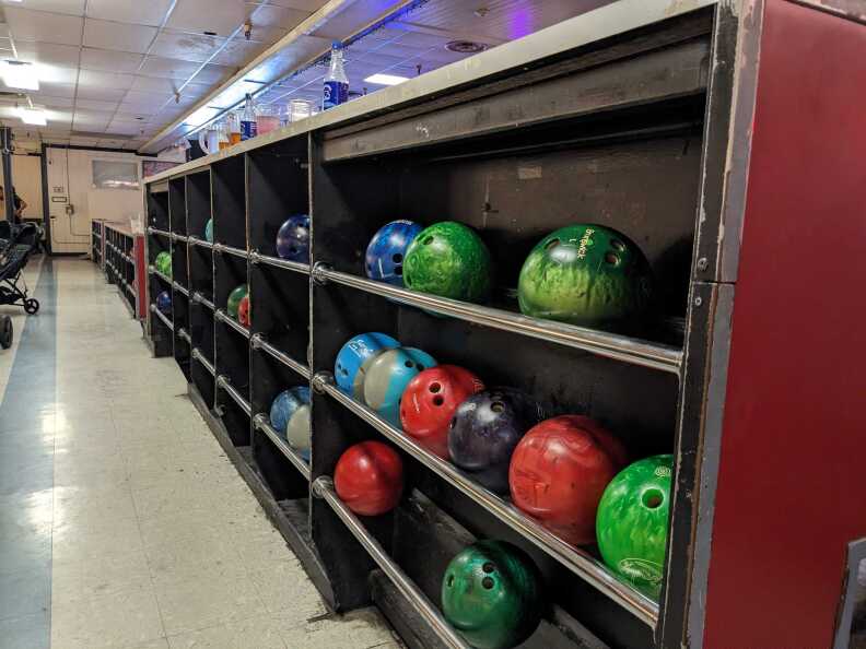 A bowling ball cabinet filled with bowling balls of different colors.