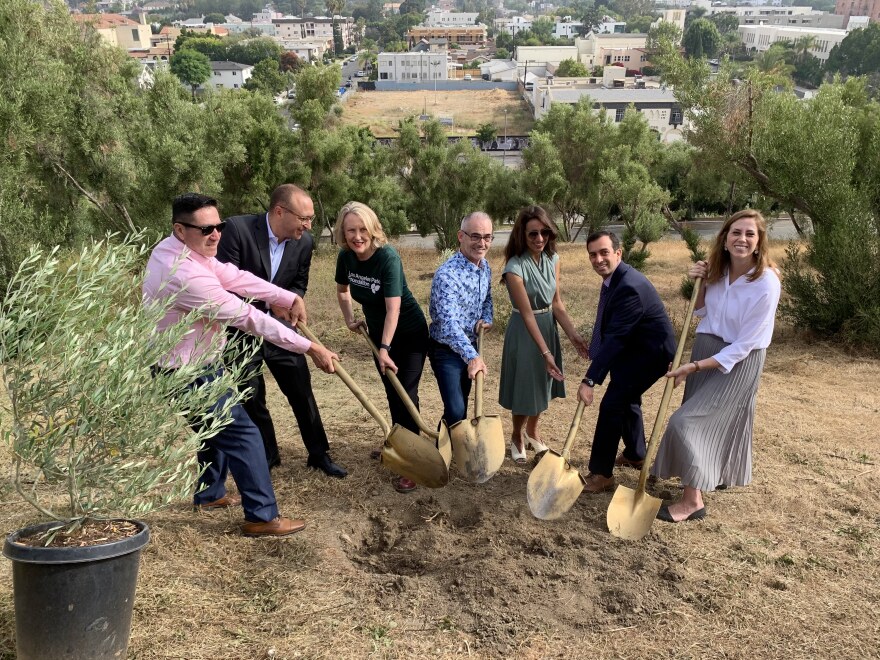 A group of people pose for a photo with golden shovels pointing outward.