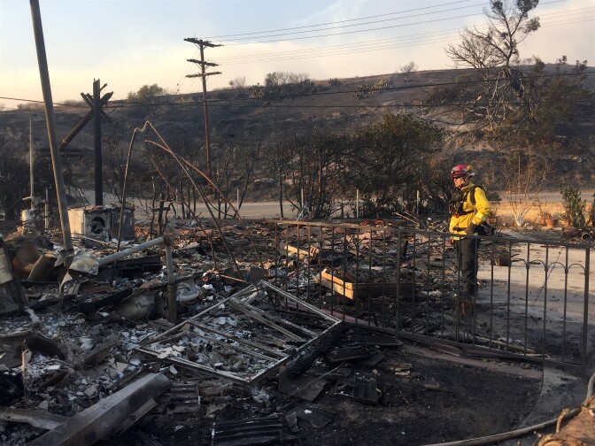 Firefighters stand in the rubble of a home on the corner of Foothill and Day Roads in Ventura. 