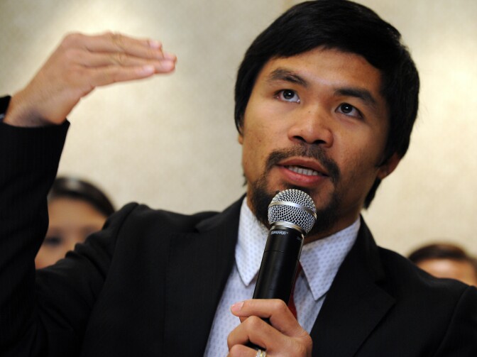 Philippine boxing icon Manny Pacquiao gestures as he speaks while two members of his battery of lawyers (back) listen during a press conference in Manila on March 26, 2012. Boxing hero Manny Pacquiao said on March 26, he would pursue criminal charges against Philippine tax collectors, accusing them of harassing him with a tax suit.  AFP PHOTO/TED ALJIBE (Photo credit should read TED ALJIBE/AFP/Getty Images)