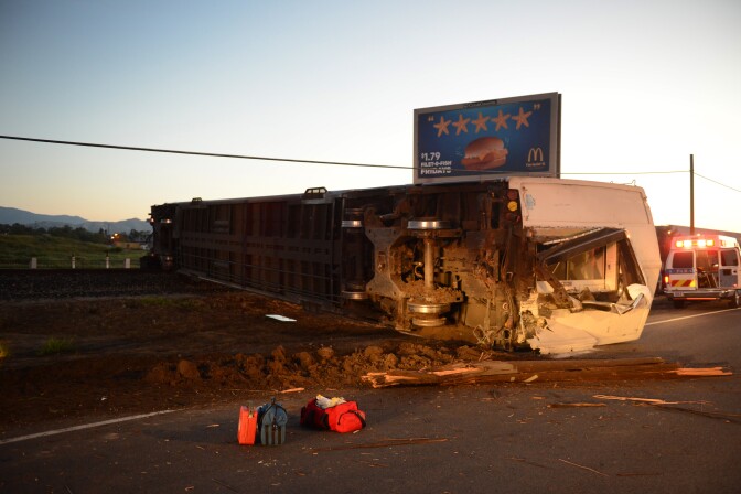 An overturned Metrolink passenger car rests on the side of the road after the train crashed into a truck and derailed early on Tuesday, Feb. 24, 2015 in Oxnard, Calif. Three cars of a Southern California Metrolink commuter train derailed and tumbled onto their sides after a collision with a truck on tracks in Ventura County northwest of Los Angeles.