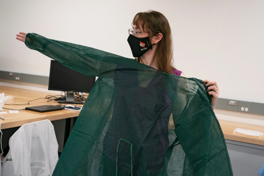 Karen Haberland, project officer at ECRI, demonstrates how a medical professional puts on a disposable isolation gown.
