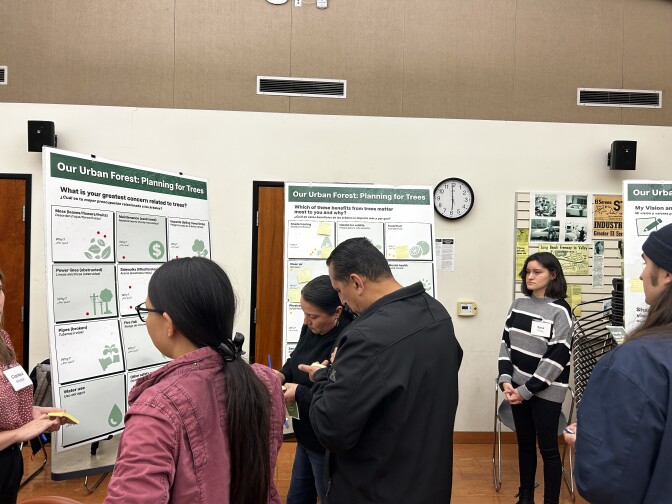Multiple people father around two large poster boards titled "Our Urban Forest: Planning for Trees." 