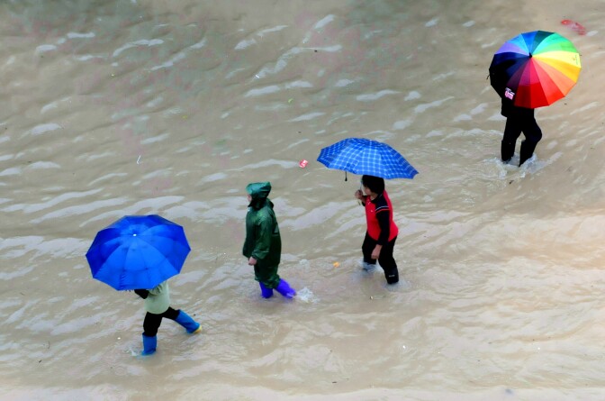 Pedestrians make their way across a street flooded by rains brought by Typhoon Haiyan in Shangsi, in southwest China Guangxi province on November 11, 2013. At least six people died after Typhoon Haiyan slashed across China's south coast and damaged hundreds of homes, state-run media on November 11, just days after devastating the Philippines over the weekend.