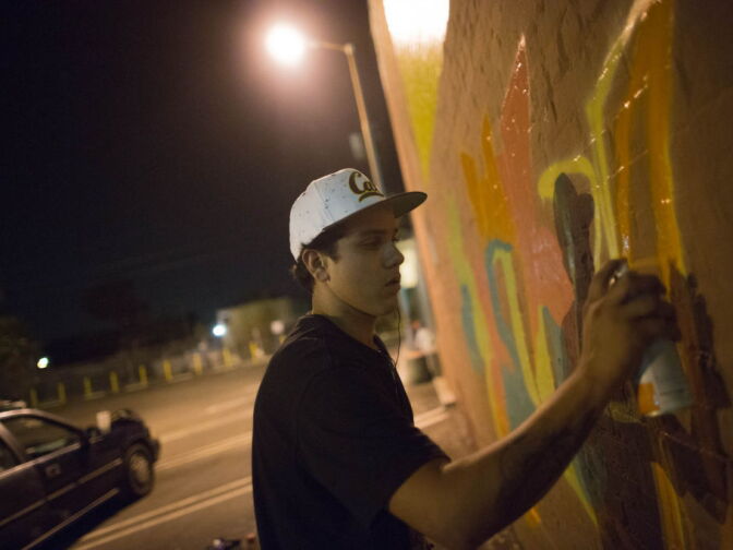 Graffiti Artist Edward Mompeller employs a fellow artist Julian, who tags a Naive, to help in creating a mural on an optical business in Highland Park.