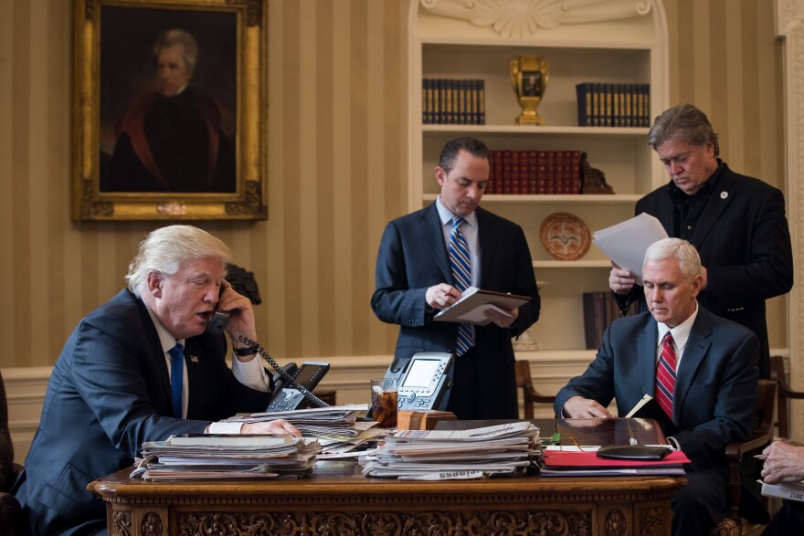 President Donald Trump speaks on the phone with Russian President Vladimir Putin in the Oval Office of the White House, January 28, 2017 in Washington, DC. Also pictured, from left, White House Chief of Staff Reince Priebus, Vice President Mike Pence, and White House Chief Strategist Steve Bannon.