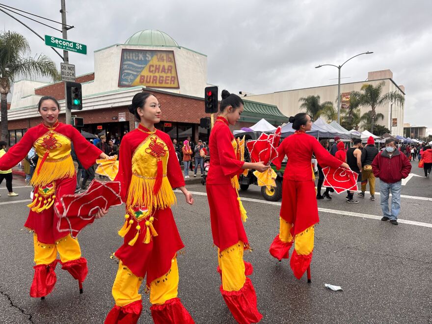Alhambra Festival dancers in red and yellow stand on stilts during the Lunar New Year Festival in Alhambra, CA.