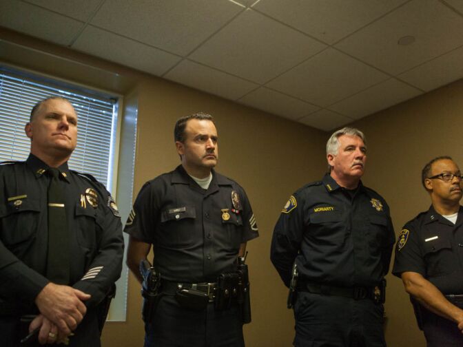 Members of the Riverside Police Department listen as officials speak at a press conference following a shooting in Riverside that left one officer dead and one injured.