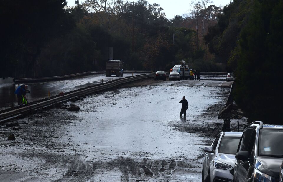 A man wades in a flooded section of the US 101 freeway near the San Ysidro exit in Montecito, California on January 9, 2018. 
Mudslides unleashed by a ferocious storm demolished homes in southern California and killed at least 13 people, police said Tuesday. / AFP PHOTO / FREDERIC J. BROWN        (Photo credit should read FREDERIC J. BROWN/AFP/Getty Images)