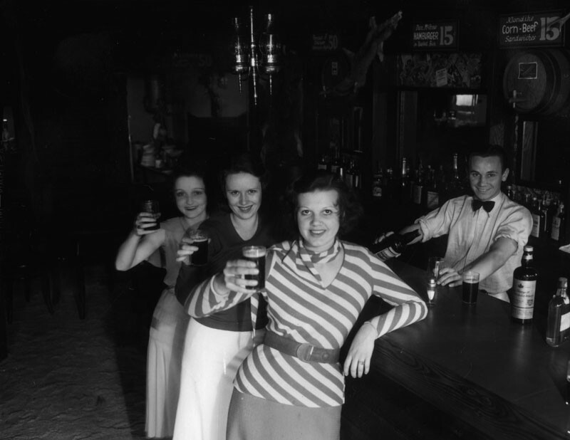 Female patrons at the Malamute Saloon, which was reportedly the first bar to open in Los Angeles after the 1933 repeal of Prohibition. The bar was designed to look like the log cabin Malamute Saloon near Fairbanks, Alaska, made famous in a poem by Robert W. Service. The L.A. version of the saloon featured a log cabin attached to a giant bottle. Circa 1933.