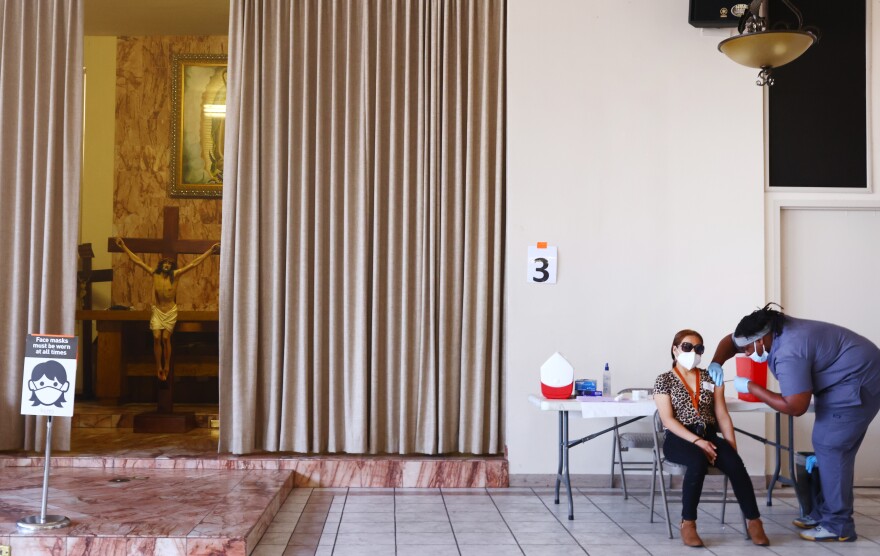 LOS ANGELES, CALIFORNIA - APRIL 09: Erendira Natalie receives her first dose of the Pfizer COVID-19 vaccine from a health care worker at a clinic targeting minority community members at St. Patrick's Catholic Church on April 9, 2021 in Los Angeles, California. St. John's Well Child and Family Center is administering COVID-19 vaccines in churches across South L.A. in a broad effort to bring vaccines to minority communities. (Photo by Mario Tama/Getty Images)