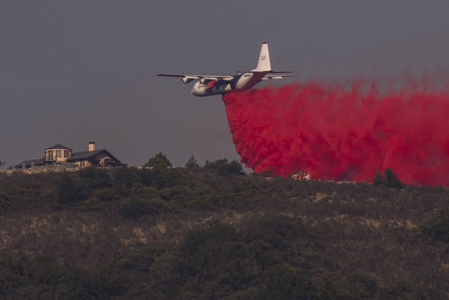 SANTA ROSA, CA -OCTOBER 15: A firefighting Coulson C-130 air tanker drops fire retardant near a house during the Oakmont Fire on October 15, 2017 near Santa Rosa, California. At least 40 people were killed with many are still missing, and at least 5,700 buildings have been destroyed since wildfires broke out a week ago.  (Photo by David McNew/Getty Images)