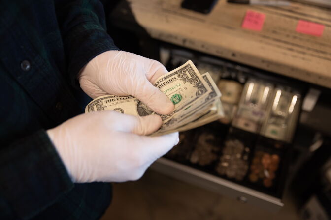 Worker seen counting money with protective gloves before mandatory close at Warehouse 4 Coffee Shop on March 15, 2020 in Vandalia, Ohio. - Ohio Governor Mike DeWine made it mandatory to shutdown all bars and restaurants starting at 9pm tonight in the state. (Photo by Brad LEE / AFP) (Photo by BRAD LEE/AFP via Getty Images)