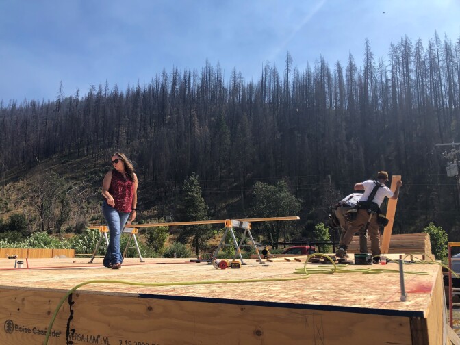 Erin Hillman supervises the reconstruction of her home, which burned to the ground in a 2020 wildfire. Rebuilding has been slow due to labor and supply shortages, plus another fire in the area.