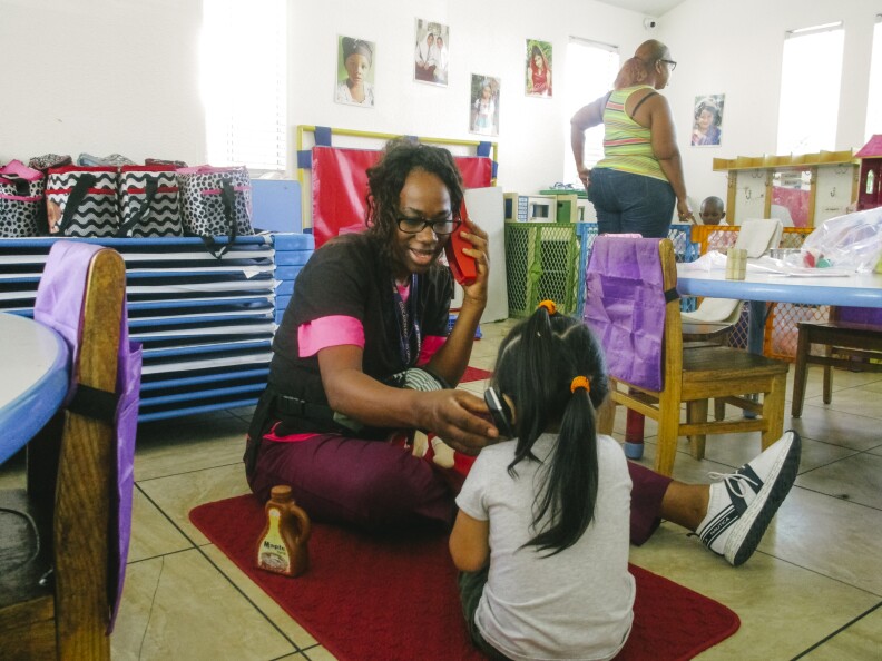 In this image, a teacher uses phones to play with a child in the classroom.