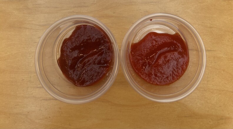 Two clear condiment cups filled with two different types of red sauce. 