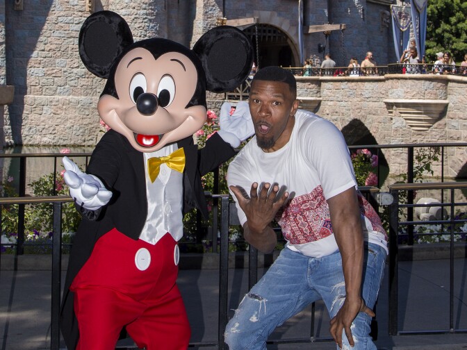 Actor Jamie Foxx meets Mickey Mouse in front of the Sleeping Beauty Castle at Disneyland in Anaheim, California on July 3, 2017.