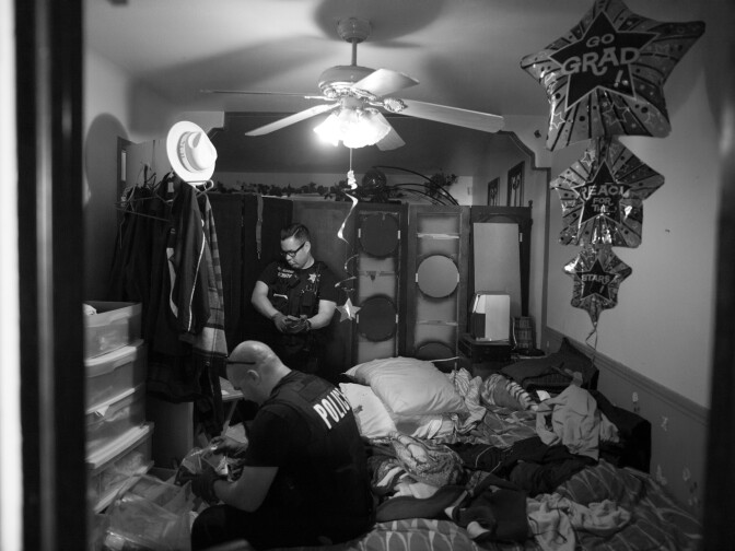 Officers look through belongings at a home in Corona, Calif.