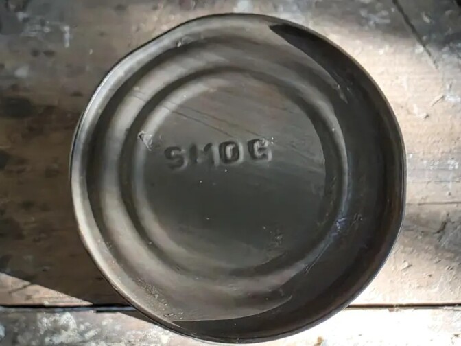 The top of a can with the word "smog" imprinted.