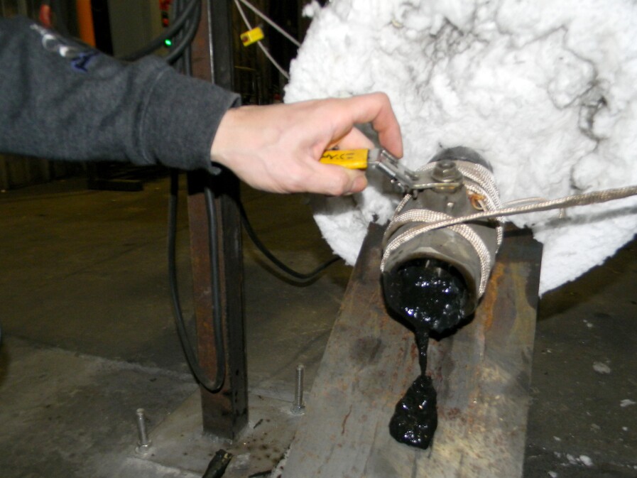 After being delivered to JBI's Plastic2Oil facility, shredded plastic is melted down in a large tank before being vaporized and formed into fuel. John Bordynuik releases some of the substance to check for quality.