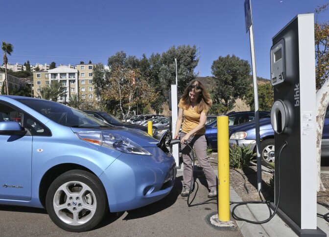 Angie Vorhies plugs in the charging cord to her Nissan Leaf electric vehicle at a San Diego mall in November 2013.