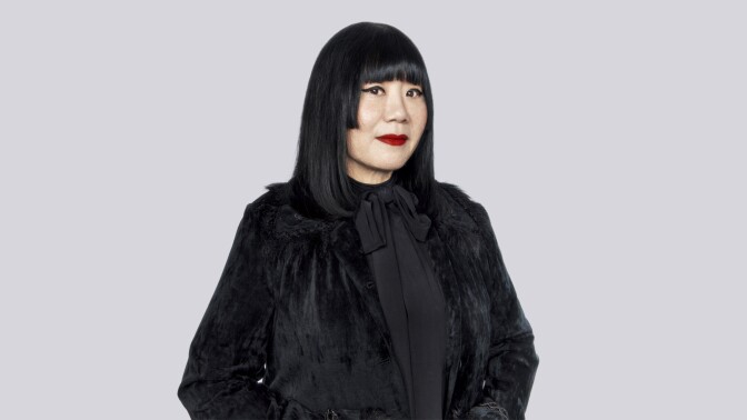 A light-skinned woman wearing all black looks at the camera. 