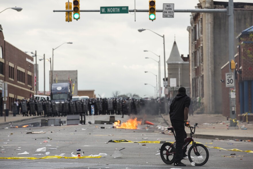 BALTIMORE, MD - APRIL 27:  With Baltimore Police officers in riot gear lining the street, a man stands at the corner of Pennsylvania Avenue and North Avenue , April 27, 2015 in Baltimore, Maryland. Riots have erupted in Baltimore following the funeral service for Freddie Gray, who died last week while in Baltimore Police custody. (Photo by Drew Angerer/Getty Images)