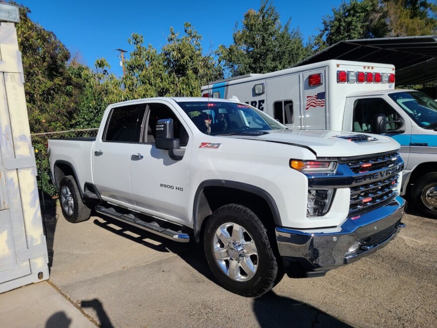 A white Chevrolet truck that's parked outside near an ambulance.